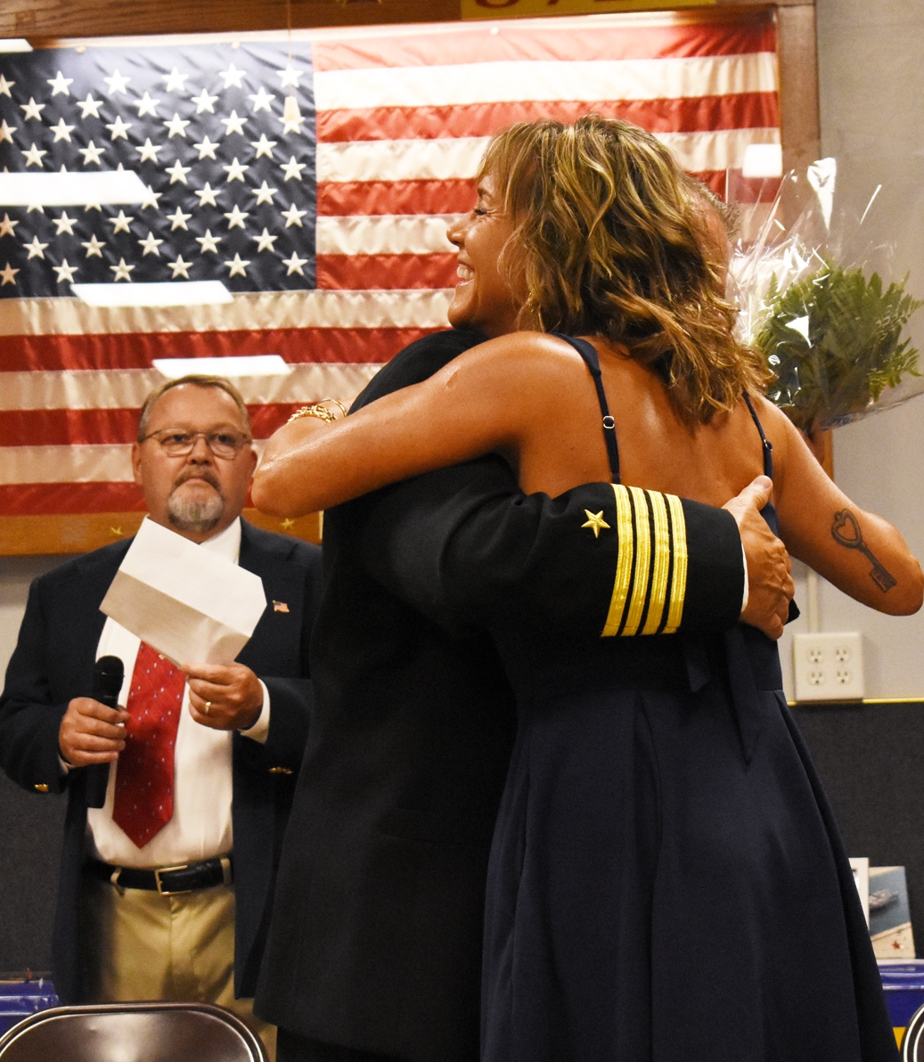 Capt. Monty Vikdal and his wife, Tiffany, embrace after Tiffany was presented with a bouquet at Monty’s promotion ceremony. At left is emcee Bill Stemper.