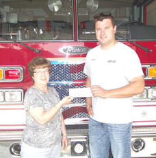 Barb Kobs (left), member of the Operation Round-Up Board at Goodhue County Cooperative Electric Association, presents a check for $1,000 to Brandon Herzig of the Lake City Fire Department.